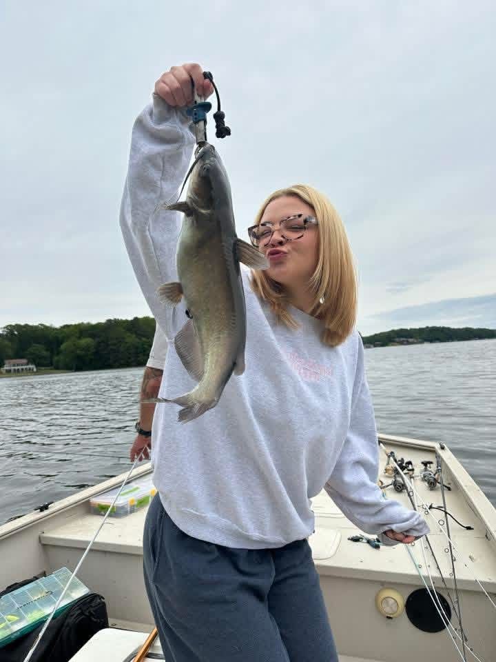 Person holding up a large fish on a boat on Lake Gaston and cloudy sky in the background.