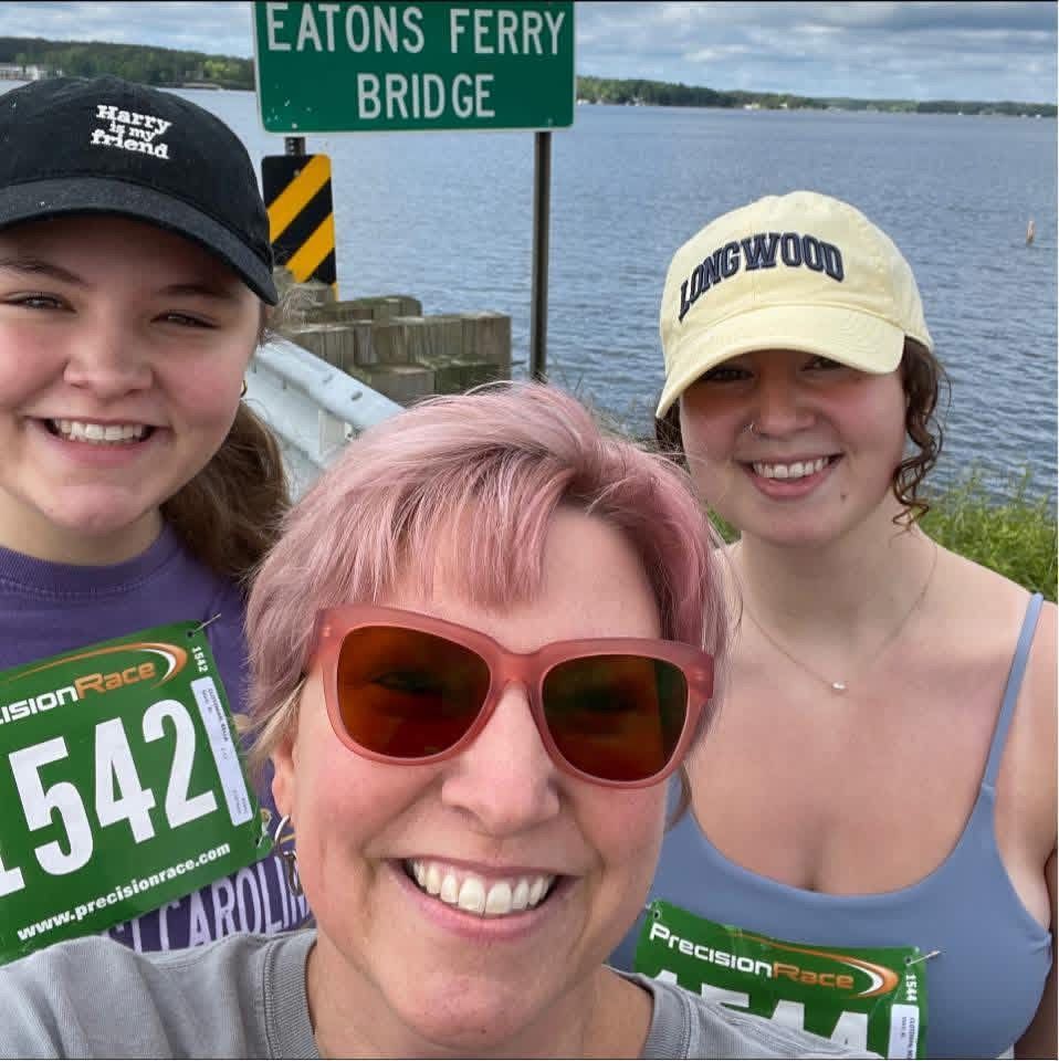 Three smiling runners posing by Eatons Ferry Bridge over the water at Lake Gaston.