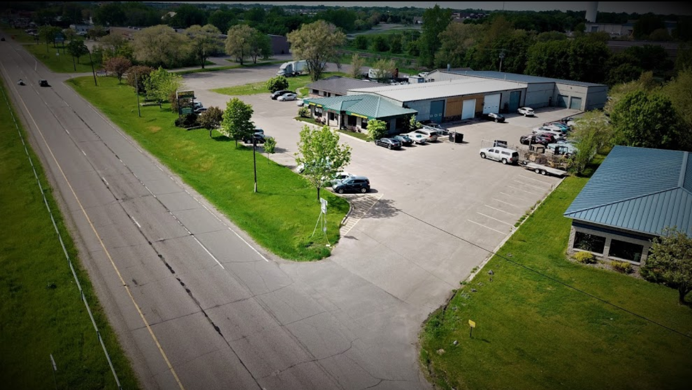 An aerial view of a parking lot next to a road and a building.