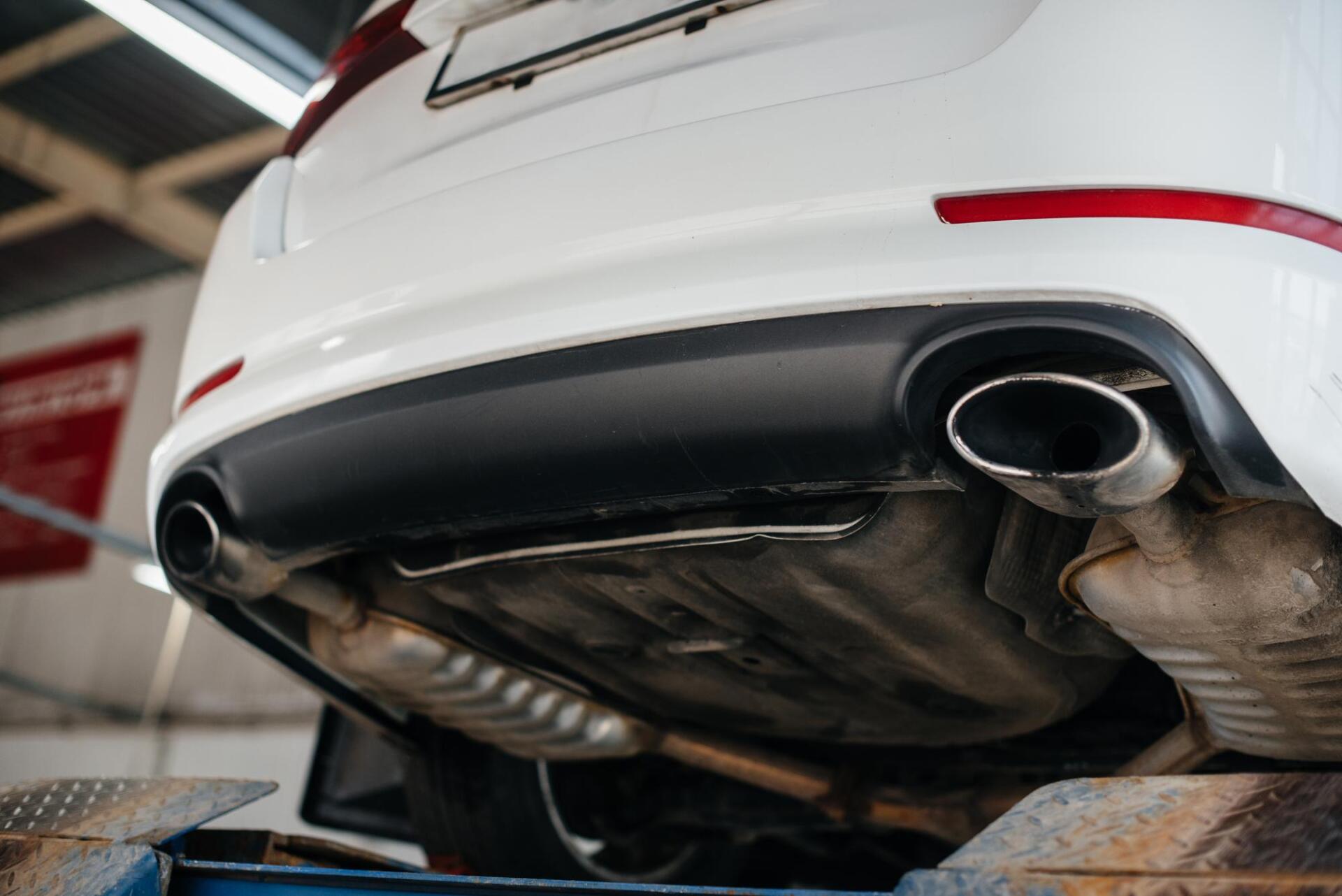 A white car is sitting on a lift in a garage.