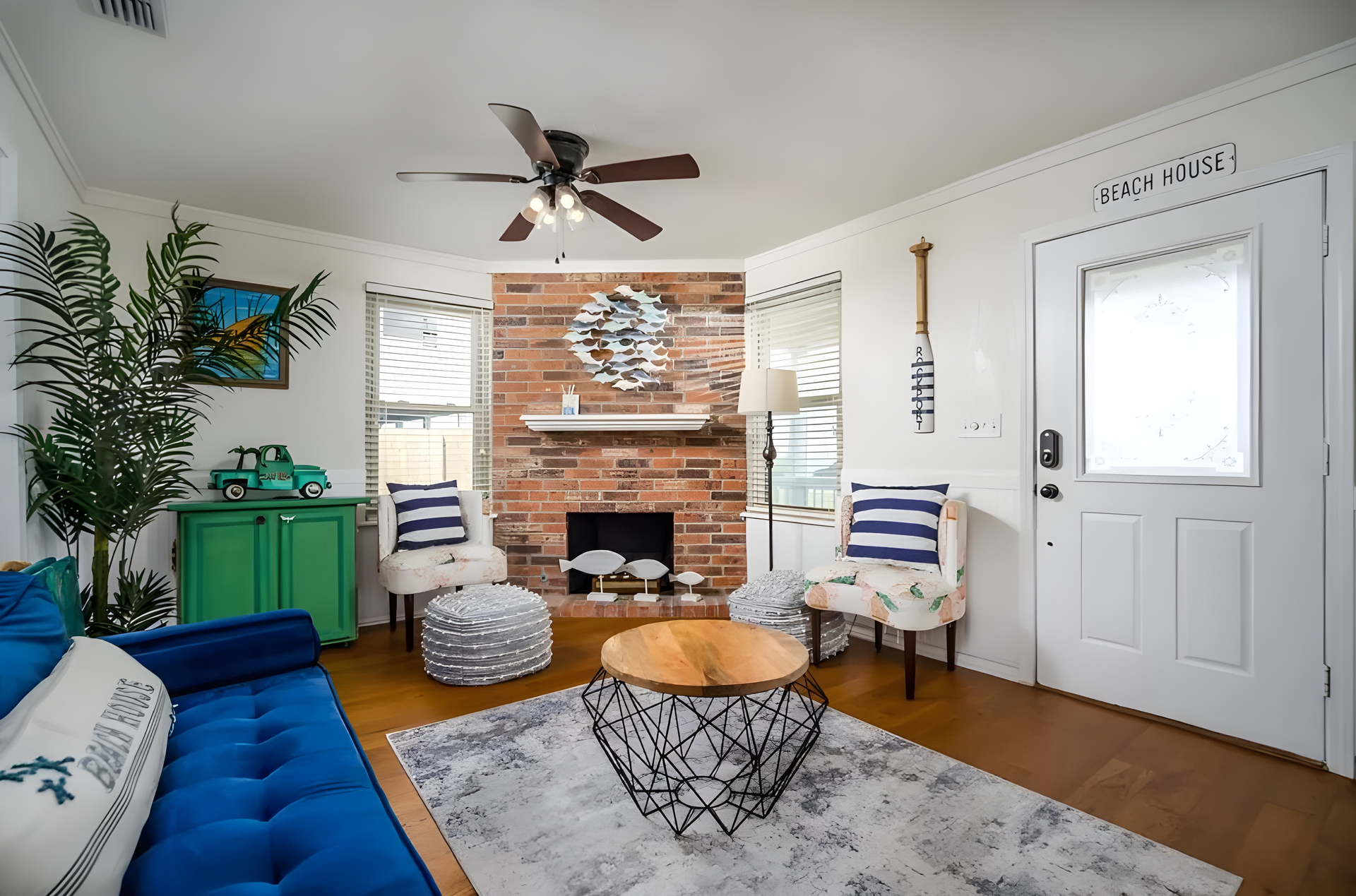 Cozy living room with blue couch, brick fireplace, and beachy decor.
