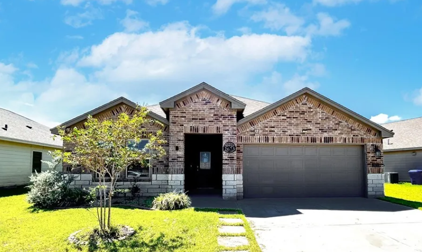 Single-story house with brick and stone facade, gray garage door, green lawn, blue sky.