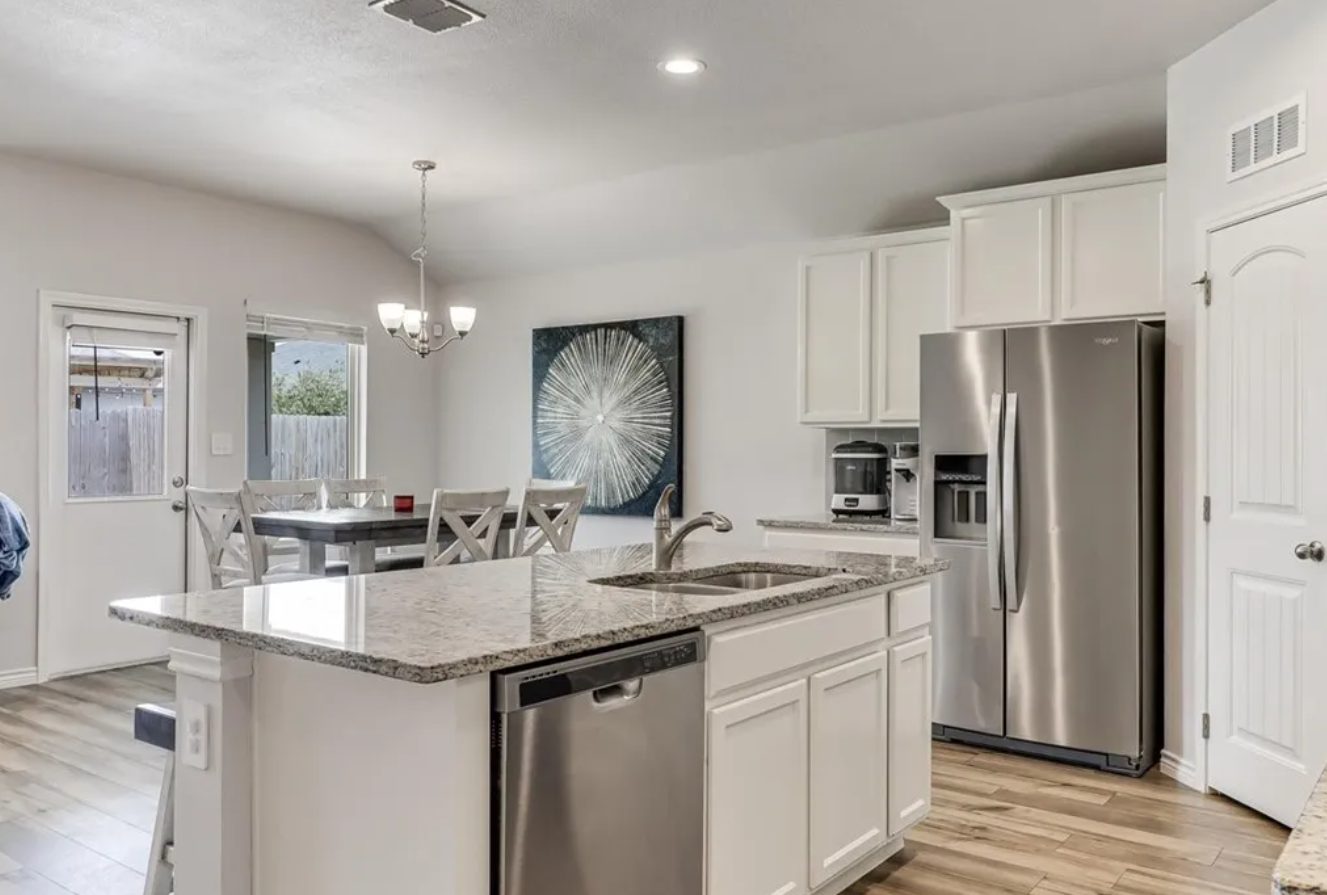 Bright kitchen with a white island, stainless steel appliances, and a dining area.