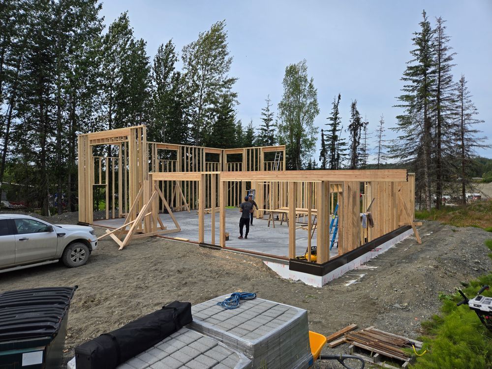 A man is standing in front of a wooden house under construction.