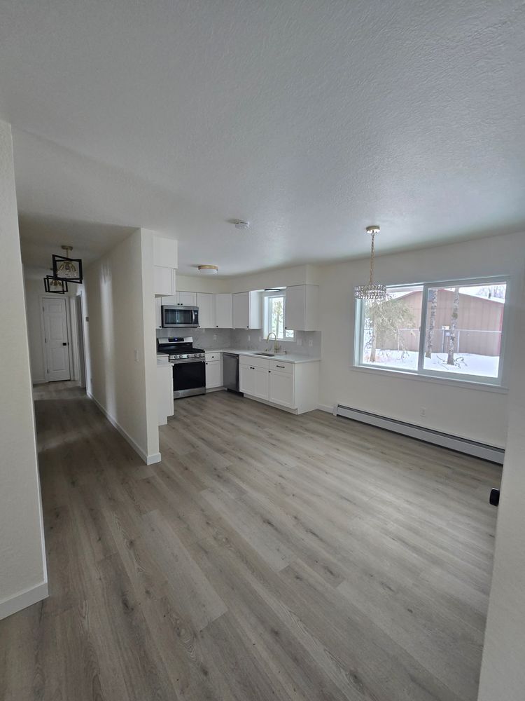 A living room with hardwood floors and a kitchen in a house.