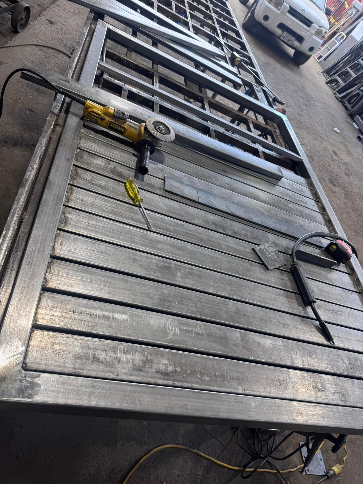 Metal gate frame under construction, with a grinder and welding torch.