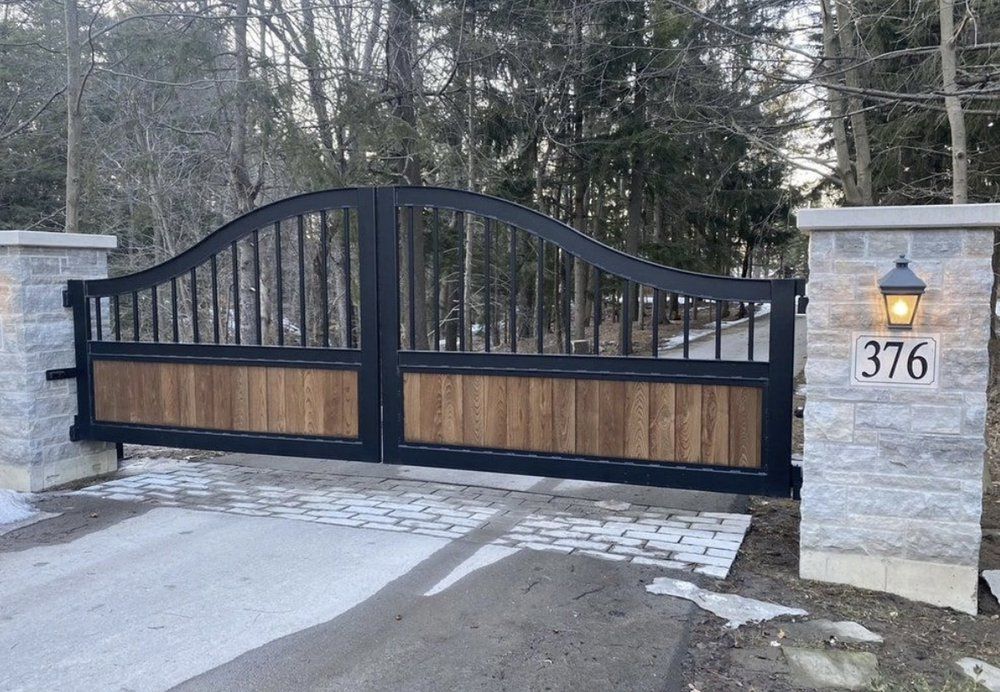 Black metal gate with wood panels, brick pillars with address 376, and paved driveway.