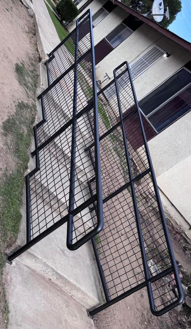 Two black metal bed frames leaning against a building's exterior wall.