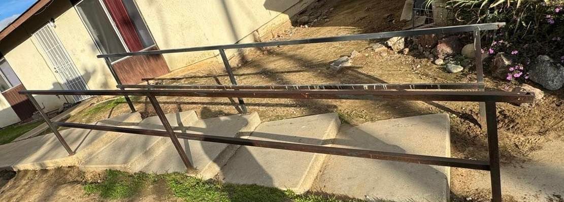 Metal frame structure resting on a concrete surface near grass.