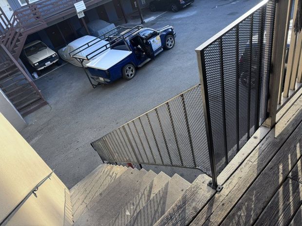 Staircase descends to a parking area with a police truck and other vehicles.