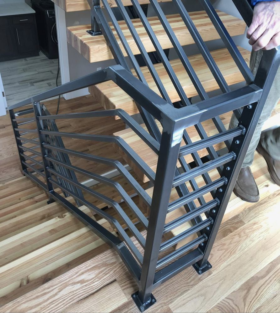 Metal staircase railing with a unique geometric design, held by a person.
