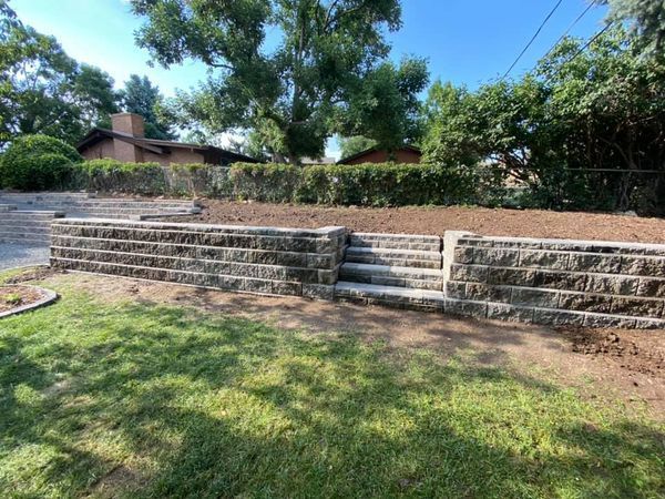 A stone wall with stairs leading up to it in a yard.