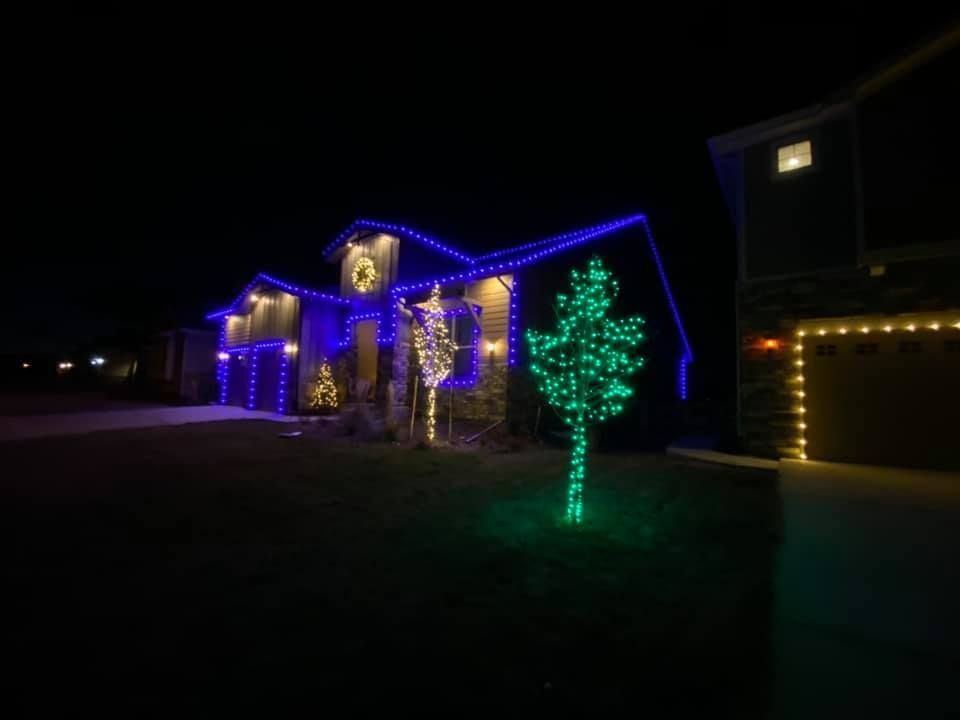 A house with christmas lights on it is lit up at night.
