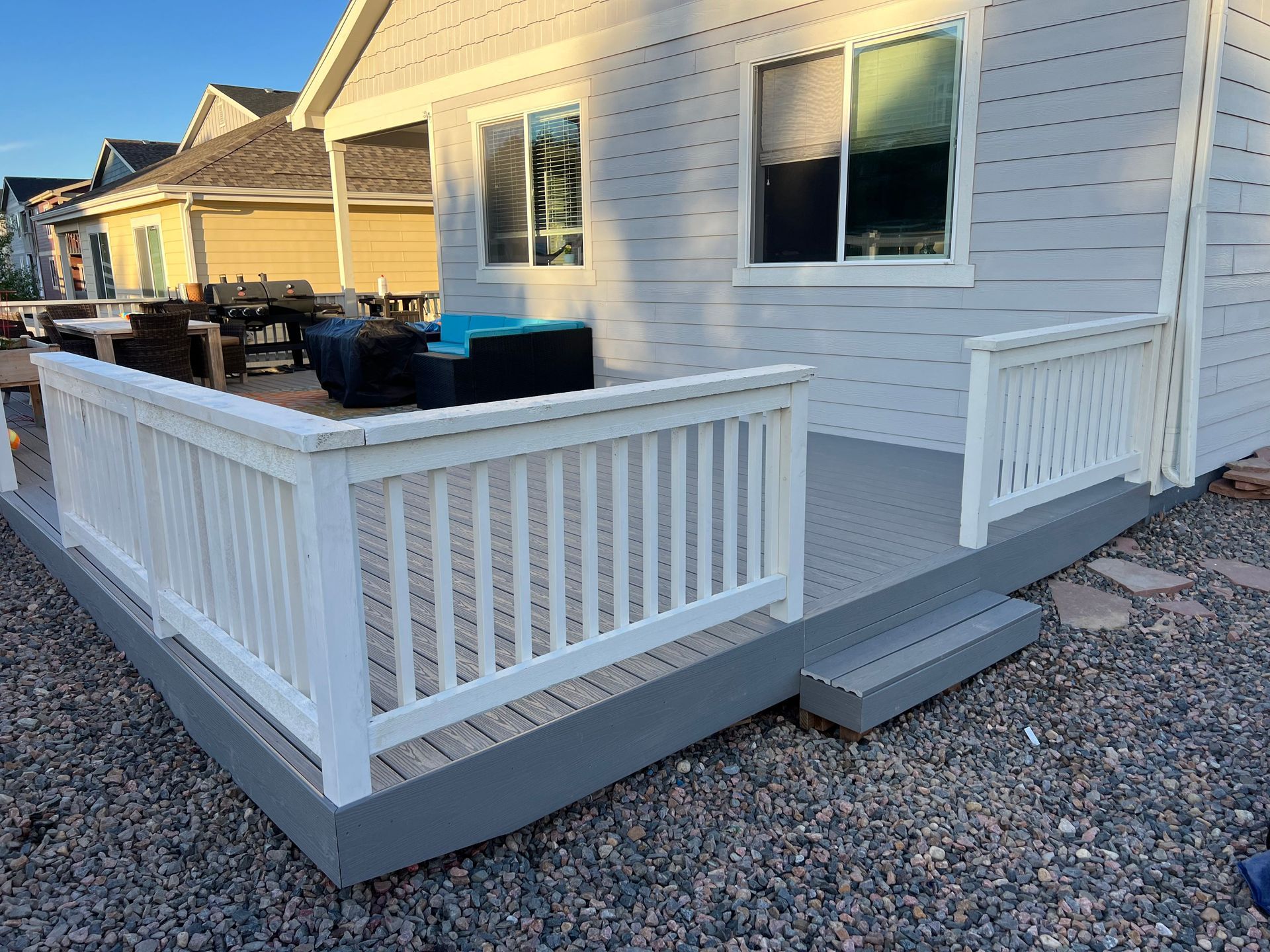 A white house with a large deck with a white railing.