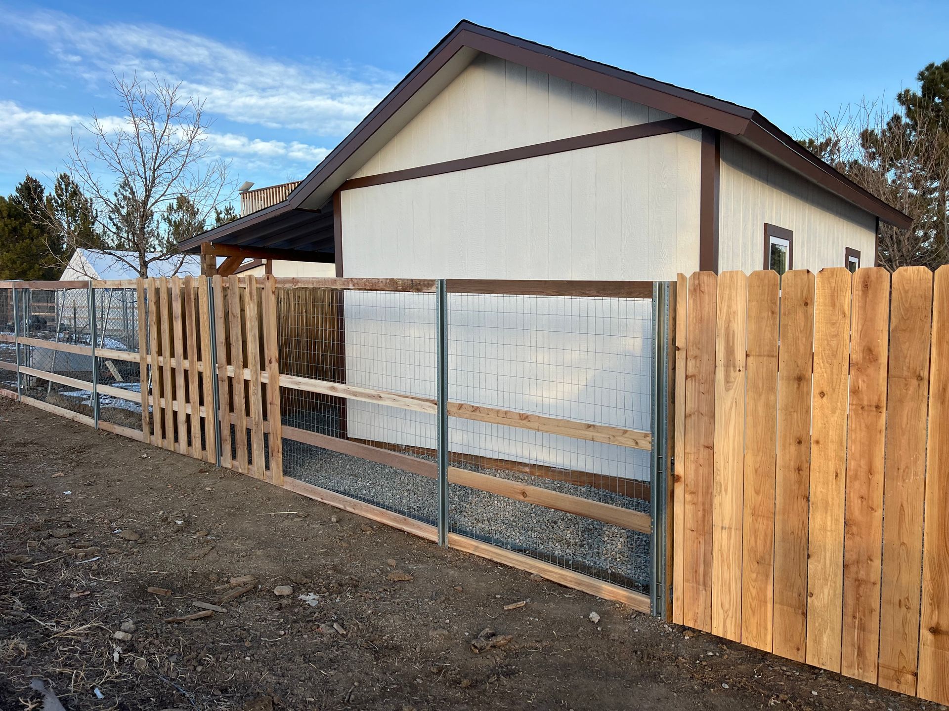 A wooden fence is surrounding a white house.
