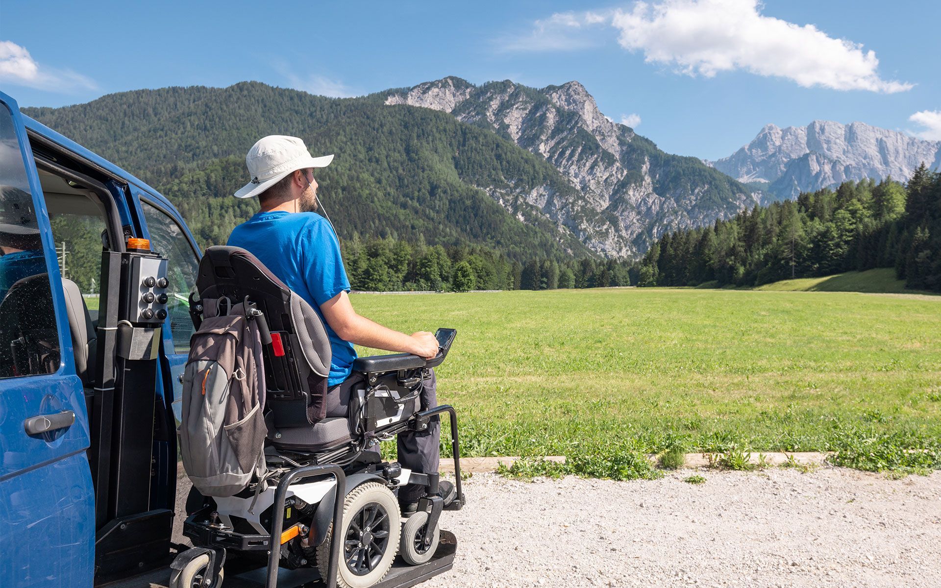 Man in wheelchair looking at mountains from blue van.