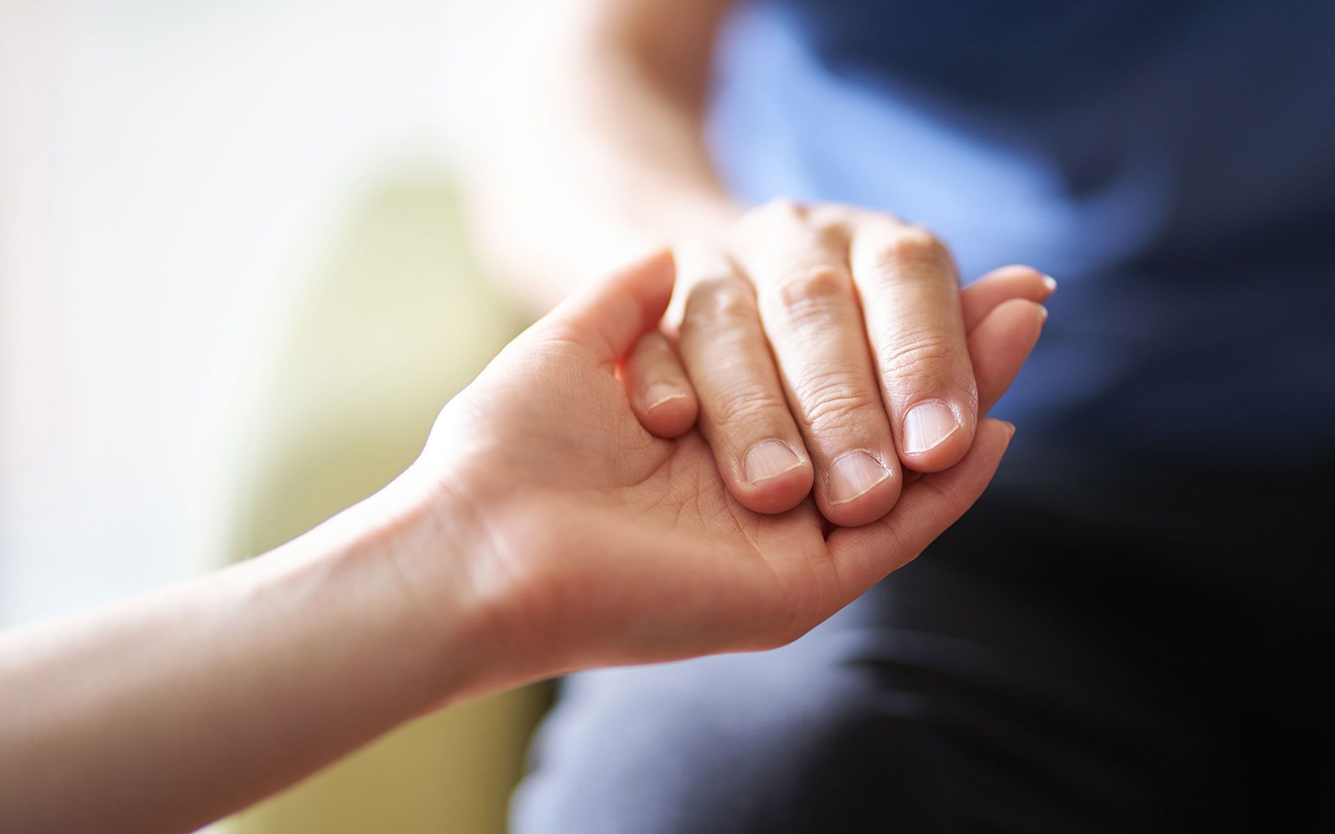 Two hands, one holding the other in a comforting gesture.