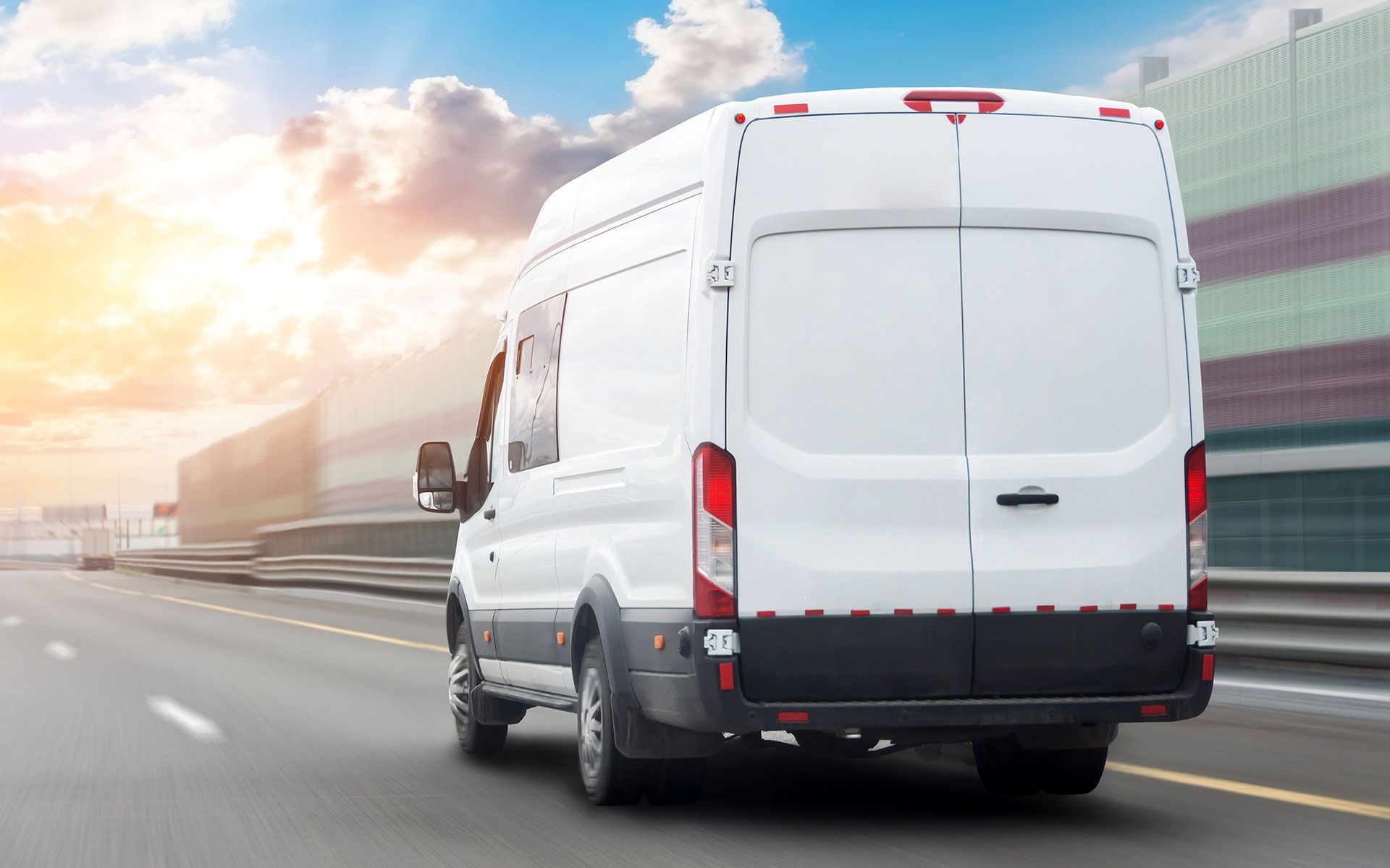 White delivery van driving on a highway, sunny day.