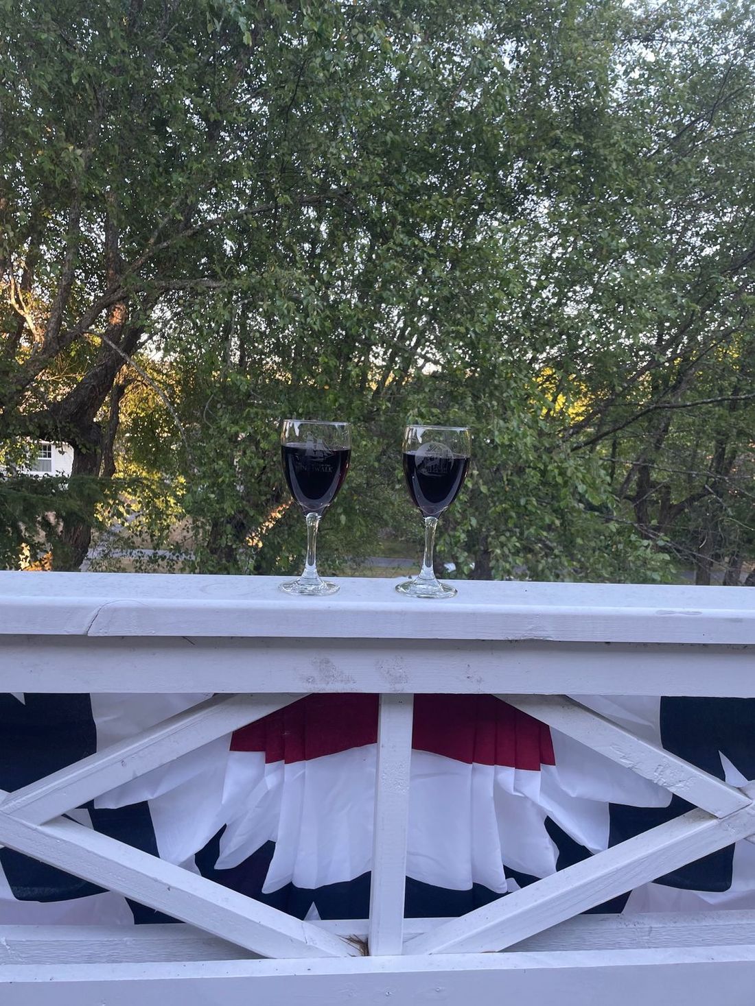 two glasses of wine on the porch railing