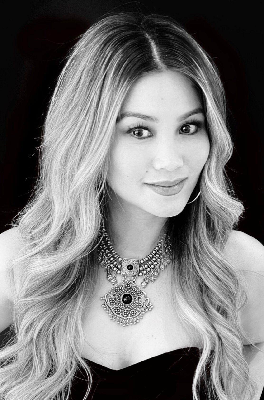 A black and white photo of a woman wearing a necklace.