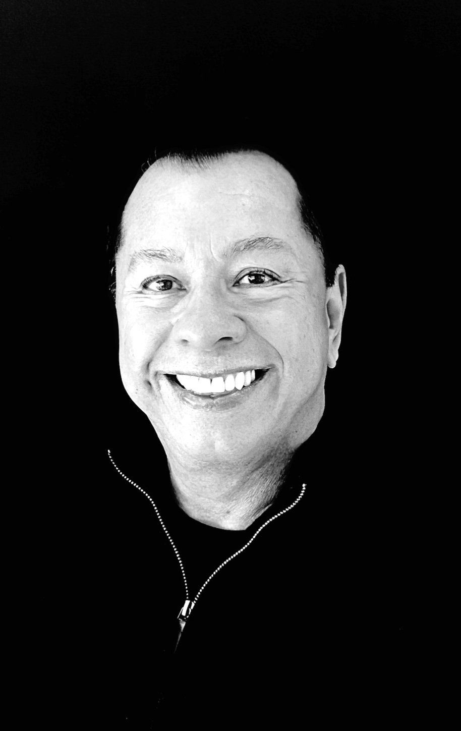 A man is smiling in a black and white photo.