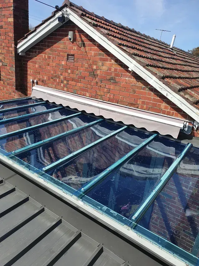 Glass roof panel on a tiled roof, next to a red brick wall.
