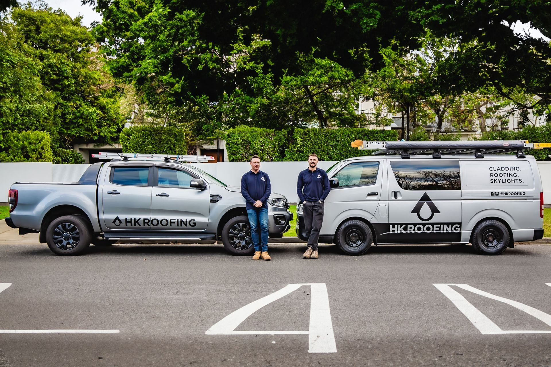 Two men stand by a truck and a van labeled