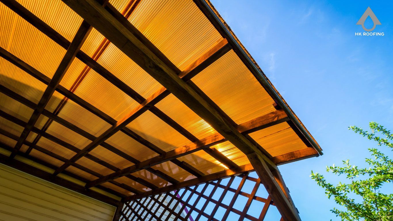 Wooden pergola with a golden-yellow translucent roof against a blue sky.