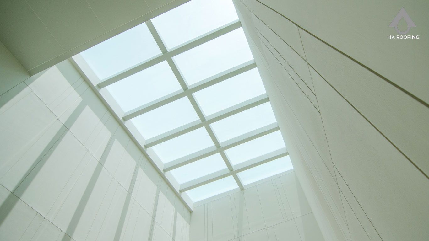 Skylight in a modern building with white walls. Sunlight streams through the glass ceiling.