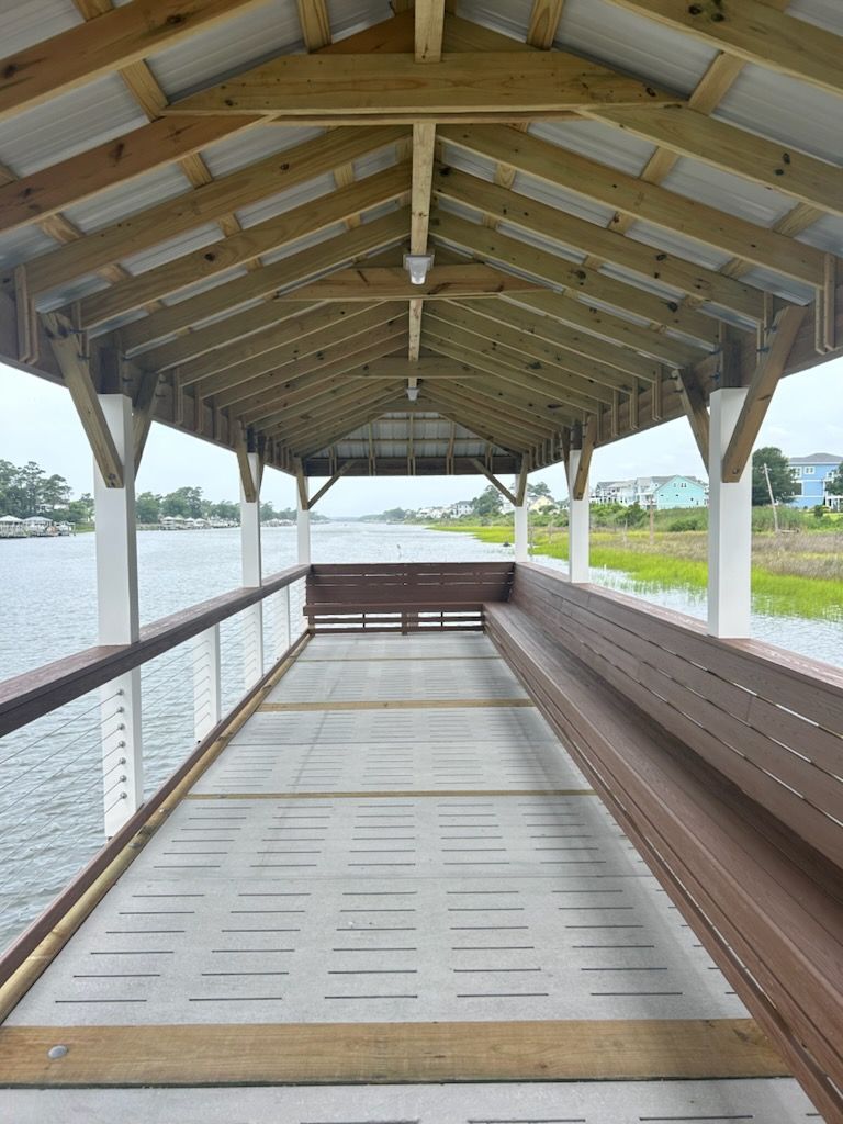 A wooden covered walkway leading to a body of water.