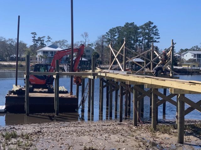 A red excavator is sitting on top of a wooden dock.
