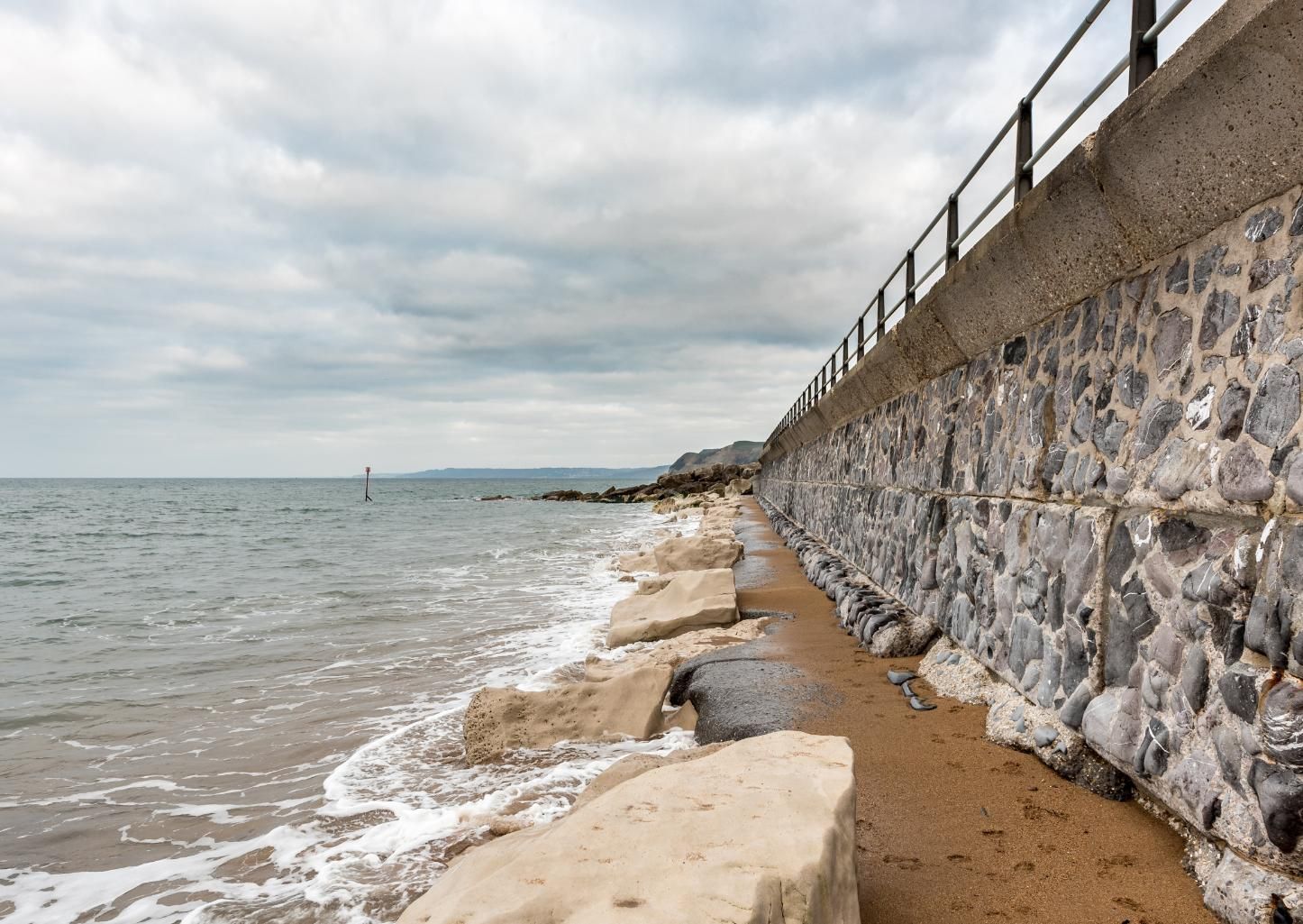 There is a stone wall along the shore of the ocean.