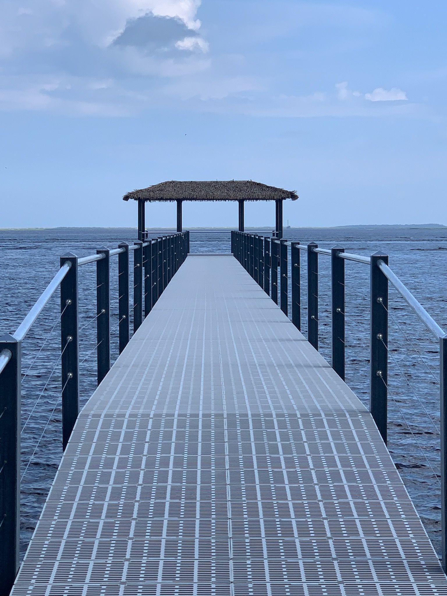 A dock leading into the ocean with a gazebo on top of it.