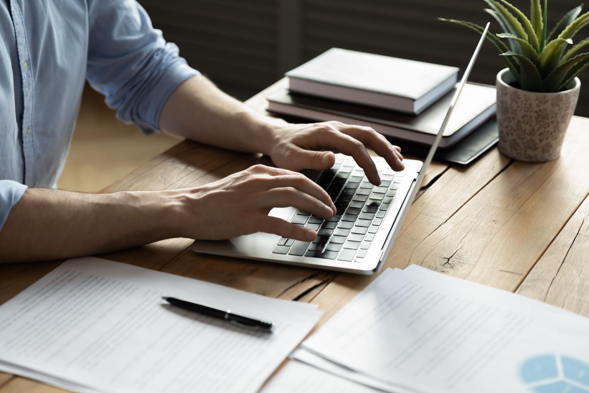 A man is typing on a laptop computer at a desk.