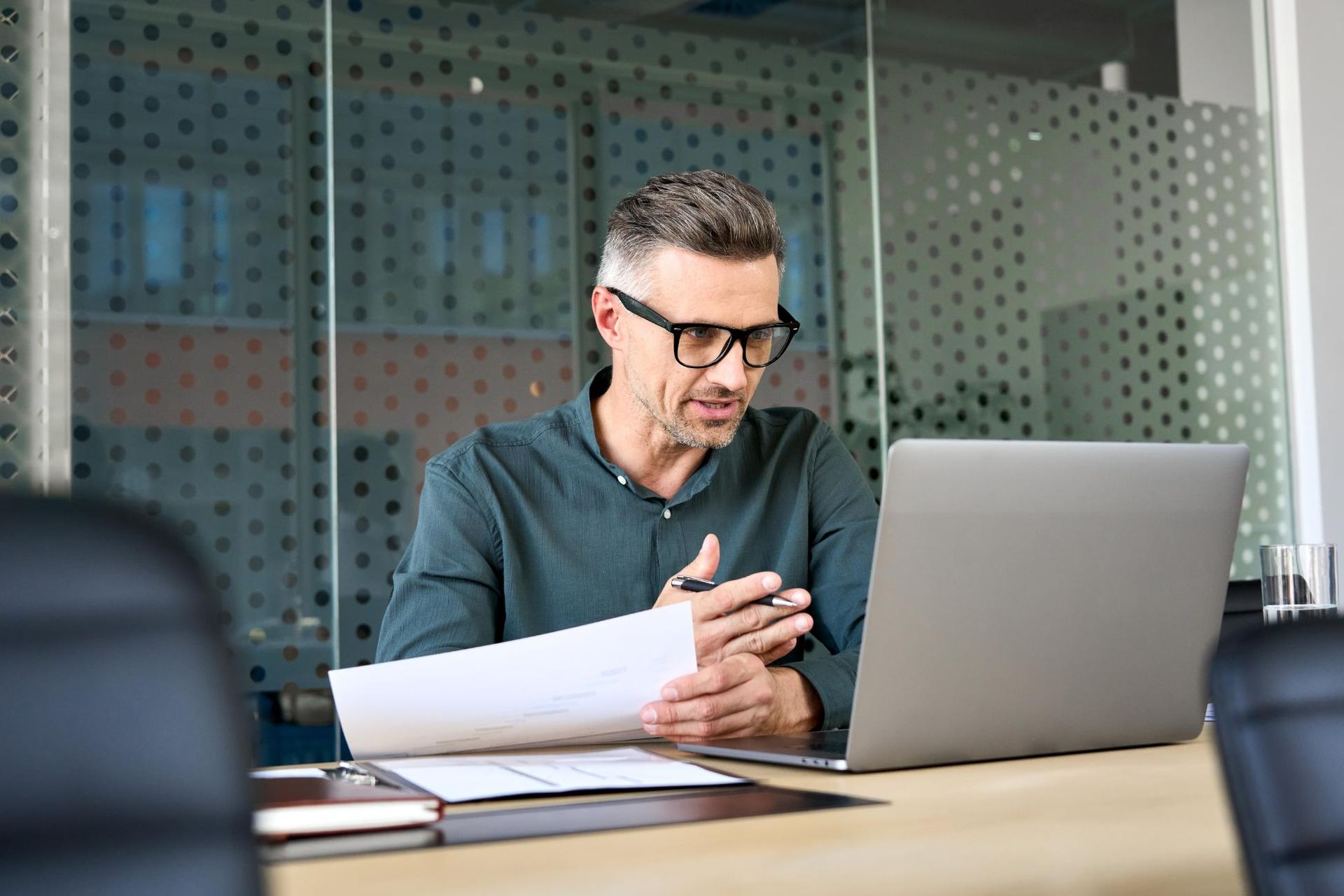 A man is sitting at a table with a laptop and a piece of paper.