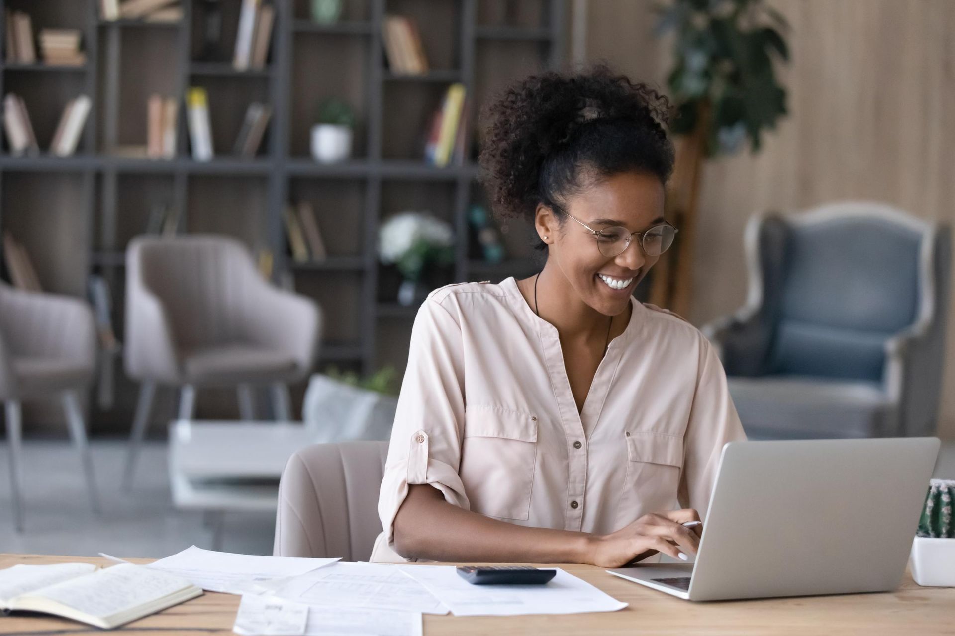 A woman is sitting at a desk using a laptop computer.