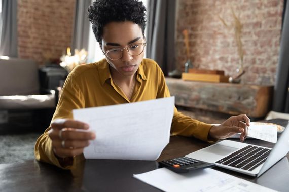 A woman is sitting at a desk looking at a piece of paper.