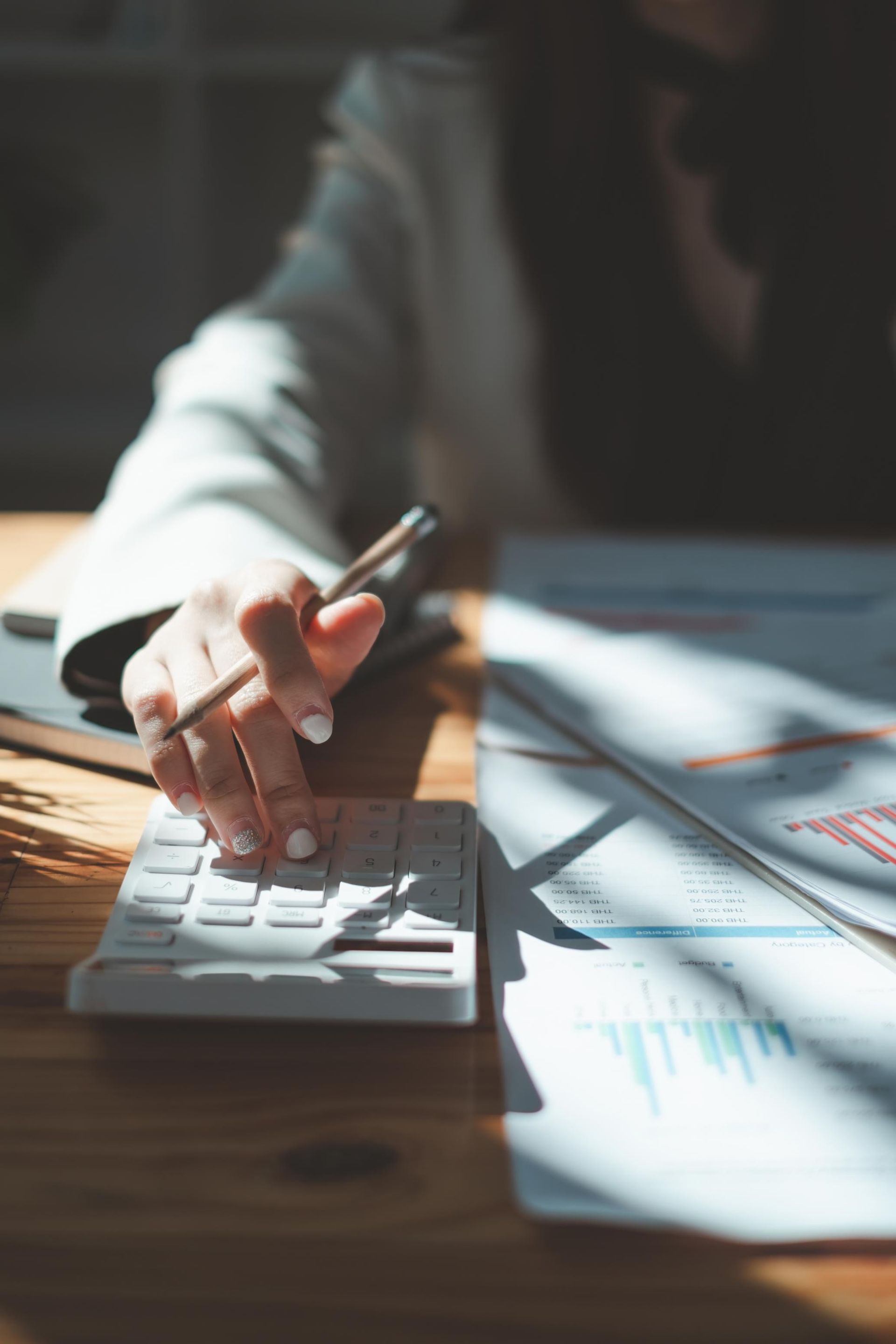 A woman is using a calculator and writing on a piece of paper.