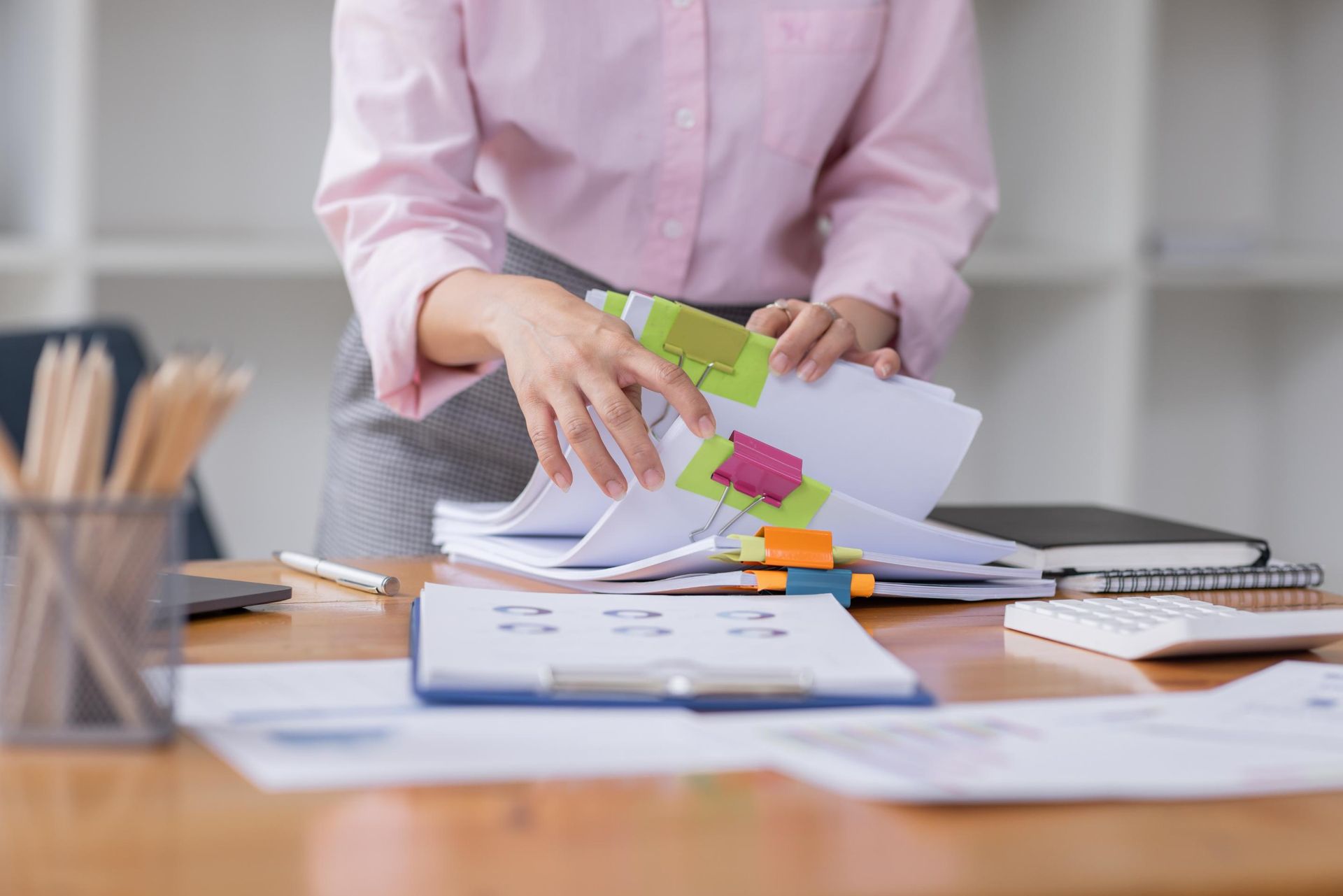 A woman is holding a stack of papers with sticky notes on them.