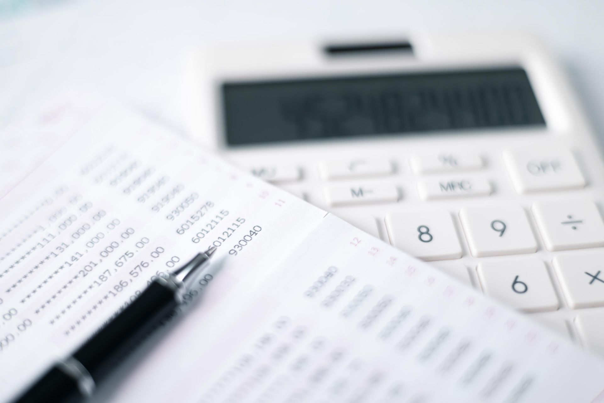 A pen is sitting on top of a piece of paper next to a calculator.
