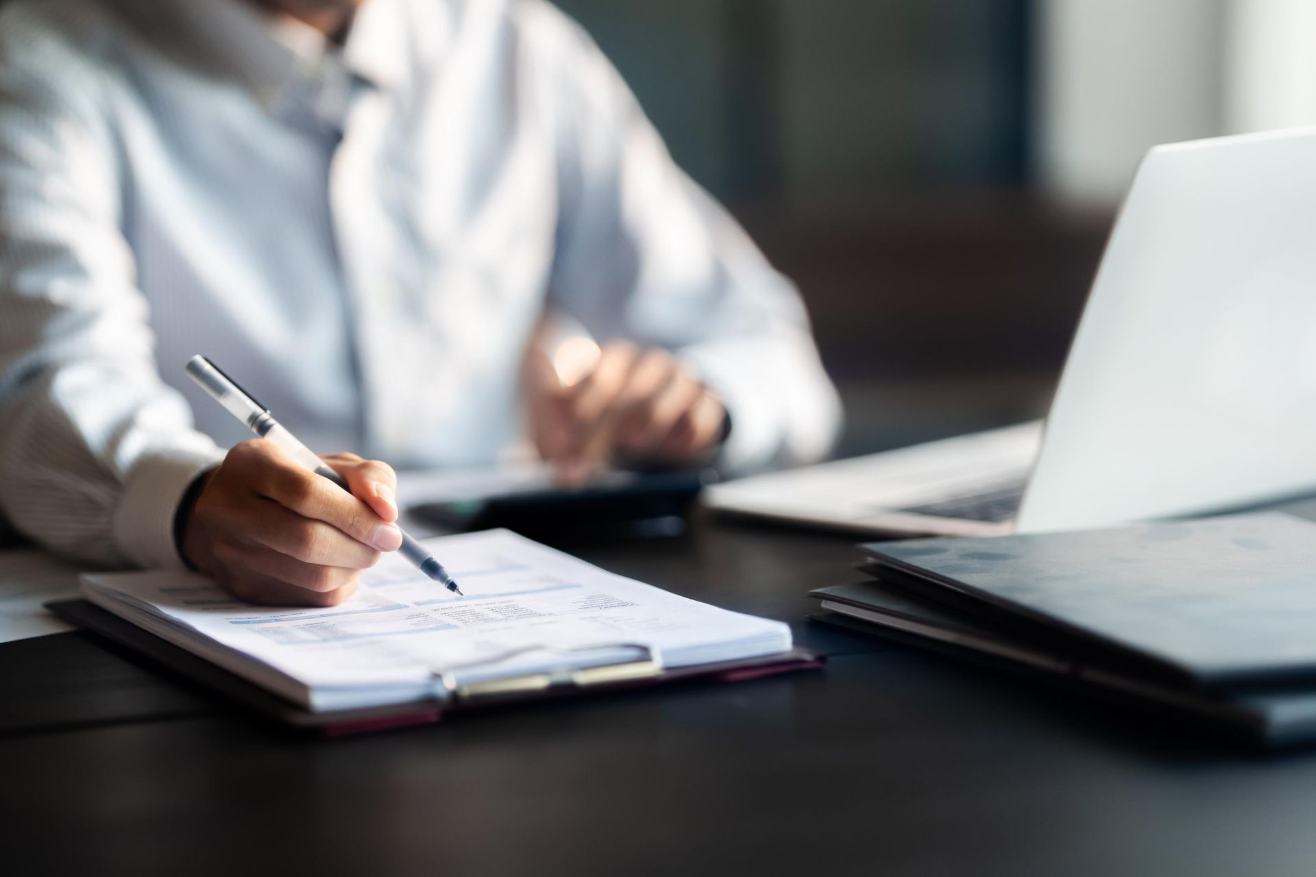 A man is sitting at a desk writing on a piece of paper.