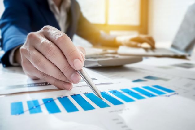 A person is using a pen to point at a graph on a piece of paper.