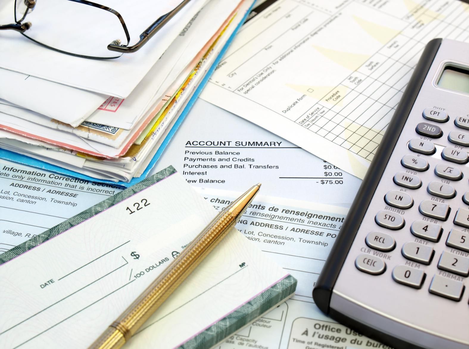 A pen is sitting on top of a checkbook next to a calculator.