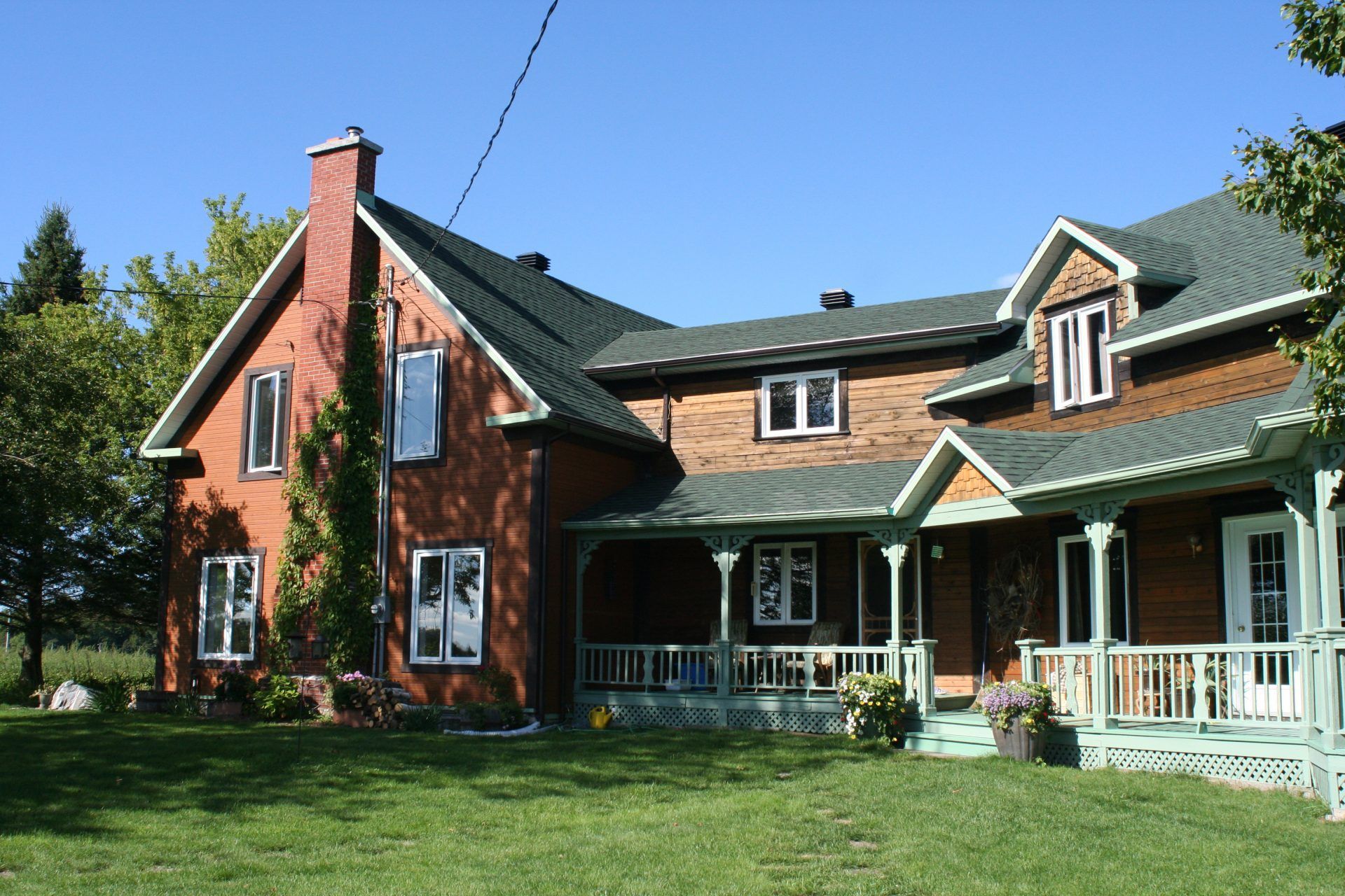 Une grande maison en briques avec un porche et une cheminée
