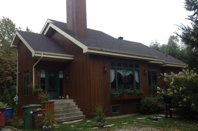 Une maison brune avec un toit noir et une cheminée