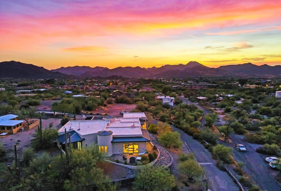 Two beds in a white room with art prints. Black and pink pillows on white bedding.
