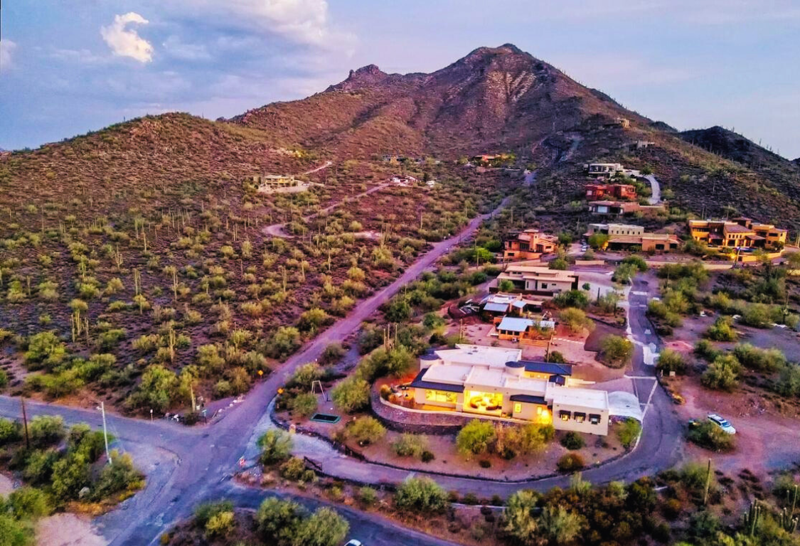 Hotel room with two beds, brick walls, desk, TV, and decorative plants.