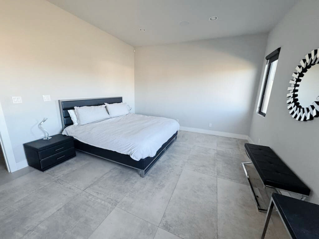 A modern open-concept living area with dark cabinetry, a large black sectional sofa, and a stone fireplace feature wall.