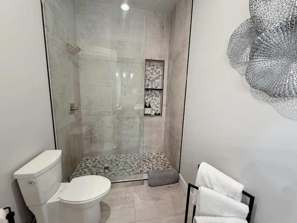 A modern living room with a large black sectional sofa, a wooden coffee table, a stone fireplace, and a mountain view.