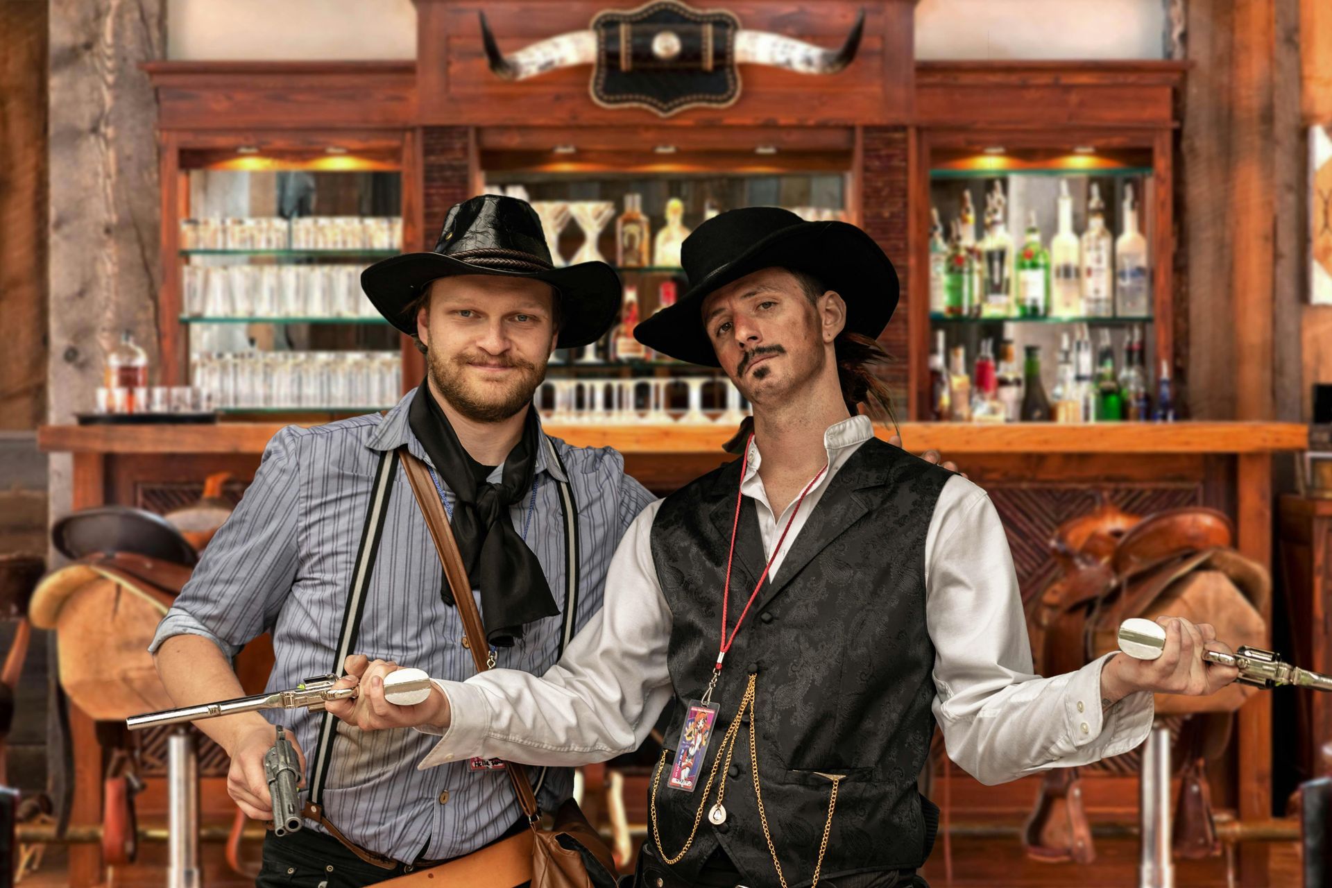 Two people in Western costumes holding toy revolvers stand in a rustic saloon behind a wooden bar.